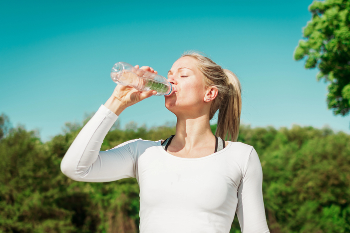 Woman drinking water outdoors, Boost NAD