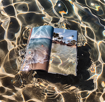 Open book floating in water with beach scenery